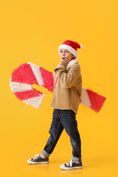 Niño sorprendido con piñata de bastón de caramelo sobre fondo de color - Foto, imagen