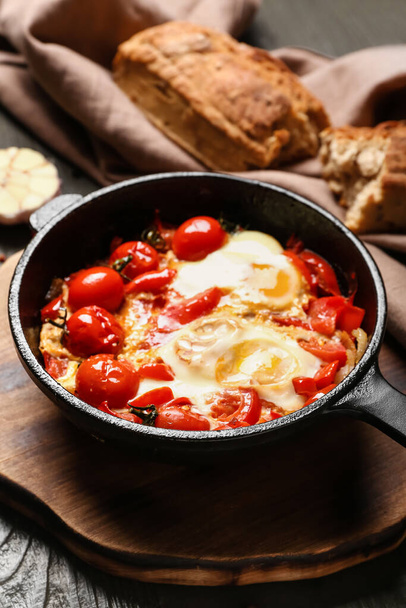 Frying pan with tasty Shakshouka on brown wooden background - Foto, afbeelding