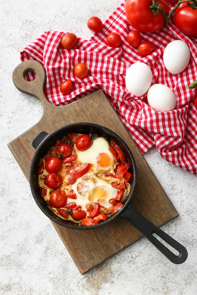 Frying pan with tasty Shakshouka and ingredients on light background - Photo, image