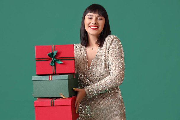 Όμορφη νεαρή γυναίκα με χριστουγεννιάτικα δώρα στο χρώμα φόντο - Φωτογραφία, εικόνα