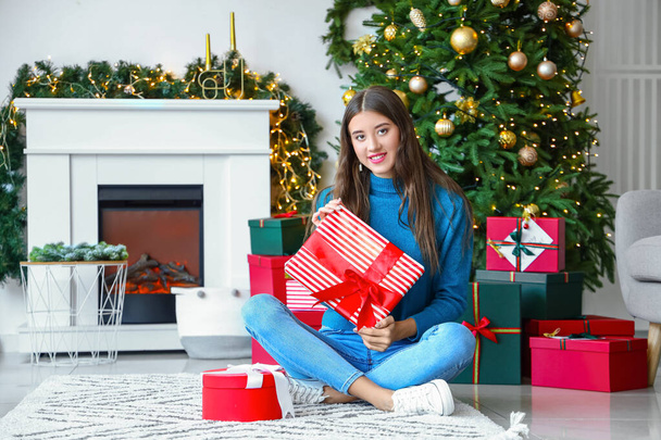 Gyönyörű fiatal nő karácsonyi ajándékokkal otthon - Fotó, kép