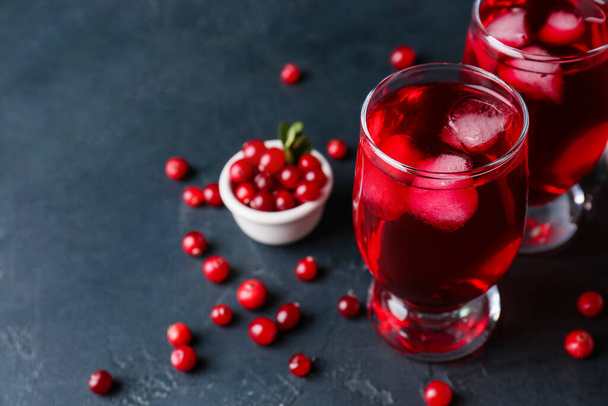 Glasses of cold lingonberry tea on dark background, closeup - 写真・画像