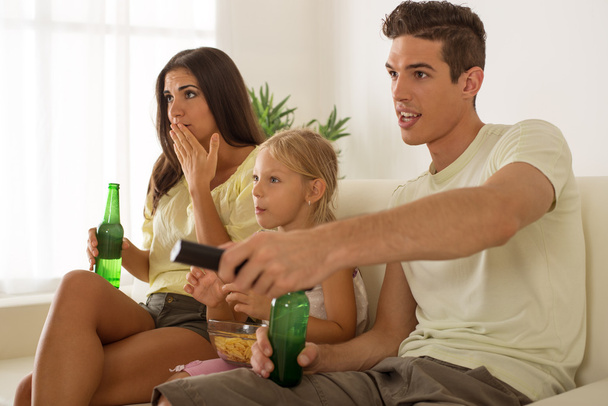 Счастливая семья дома смотрит телевизор
 - Фото, изображение