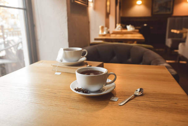 Valkoinen kuppi kuumaa teetä pussi ja lusikka pöydällä kahvilassa - Valokuva, kuva