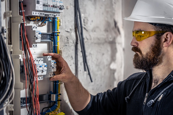 un elettricista maschio lavora in un centralino con un cavo di collegamento elettrico
. - Foto, immagini