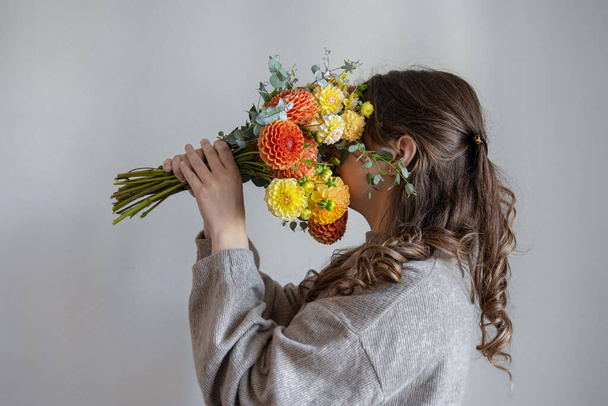Young woman with a bouquet of fresh chrysanthemums on a gray background. - Foto, Imagem