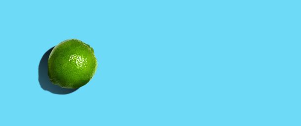 Lime on a blue background. Hard shadow. Flat lay. Copy space. Fruits. Background. - Foto, afbeelding