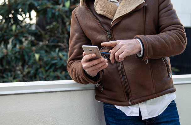 mature man in jacket using mobile phone on the street - Φωτογραφία, εικόνα