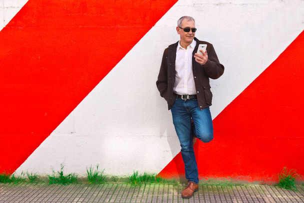 middle aged man using mobile phone on the wall - Foto, afbeelding