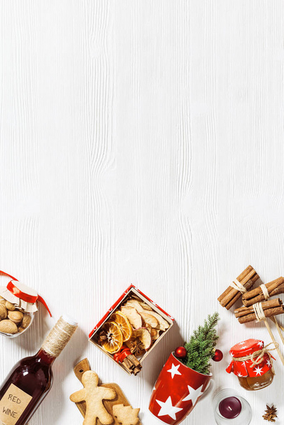 Mulled wine Ingredients as diy gift box, handmade present with dried fruits, honey, spices, christmas cookies. Red wine and red cup for christmas holiday hot winter drink on white wood. Top view. - Foto, imagen