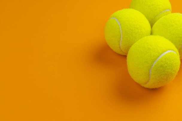 Four tennis balls on an orange background - Фото, изображение