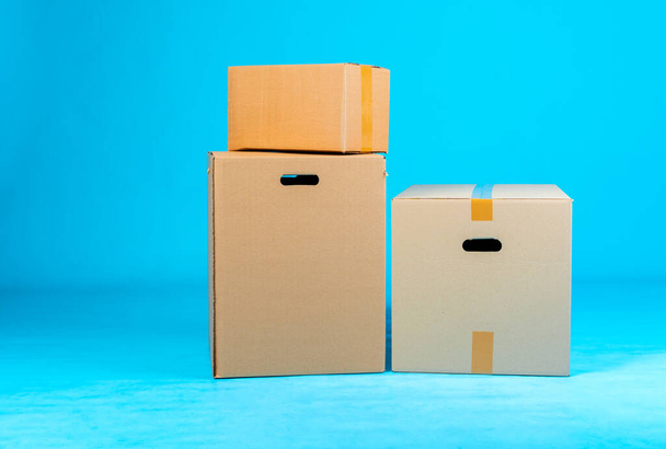 Stack of cardboard boxes on blue background - 写真・画像