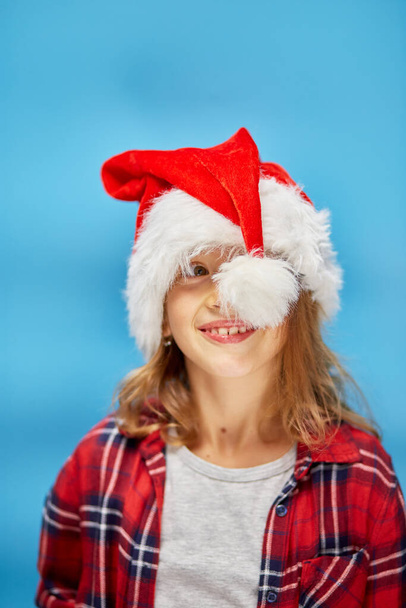 Ritratto di bambina di Natale a Santa Hat, gioioso, sorridente bambino su isolato sfondo blu studio, posto per testo, Wow faccia - Foto, immagini