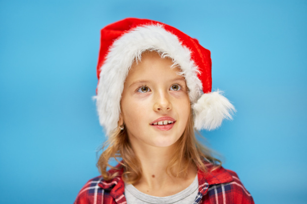 Portret dziewczynki w Santa Hat, uśmiechnięte dziecko na odizolowanym niebieskim tle pracowni, miejsce na tekst - Zdjęcie, obraz