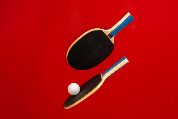 Black ping pong rackets on red background - Foto, imagen