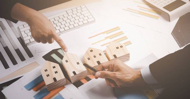 Koncepcja transakcji finansowych online, Grupa biznes Wybierz model drewnianego domu i punkt analizując dane finansowe podczas dyskusji, planowania budżetu promocyjnego, budowy domu i rynku akcji - Zdjęcie, obraz