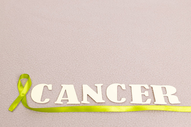 The letters spelling "Cancer" with the cancer symbol ribbon on pastel-colored fabric. - Valokuva, kuva