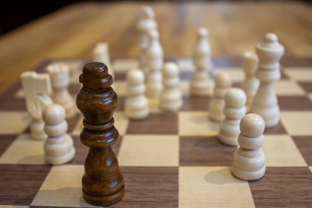 A selective shot of a king chess piece in front of the other pieces on a chessboard - Foto, Bild