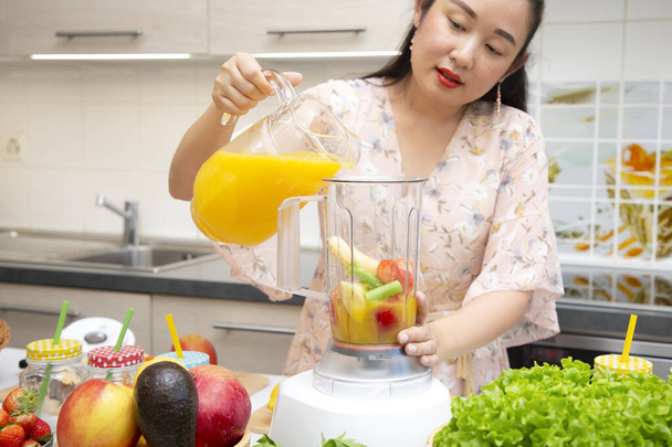 Glückliche Frauen genießen es, frisch gepresstes Obst mit Gemüse zuzubereiten, um gemeinsam in der Küche Smoothies zum Frühstück zu bereiten. Ernährungs- und Gesundheitskonzept. - Foto, Bild