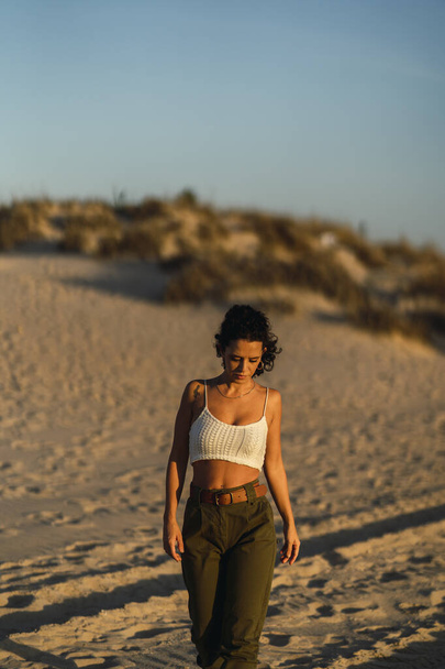 A vertical shot of a Spanish curly female posing on the sand - Φωτογραφία, εικόνα