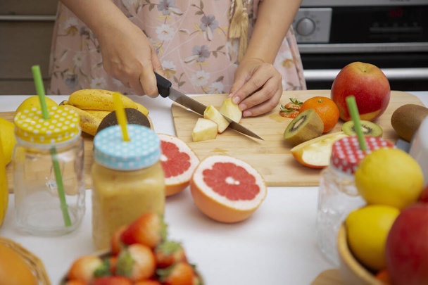 幸せな女性はキッチンで一緒に朝食のためのスムージーを作るための野菜と新鮮な圧搾フルーツを準備してお楽しみください。食事と健康の概念. - 写真・画像