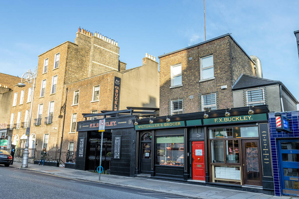DUBLIN, IRELAND - Apr 23, 2021: A shot of shops, restaurants and pubs with black exteriornear Baggot Street of Dublin during sunrise - Photo, image