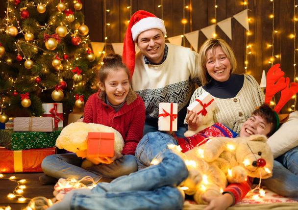 Family posing in new year or christmas decoration. Children and parents. Holiday lights and gifts, Christmas tree decorated with toys. - Foto, immagini