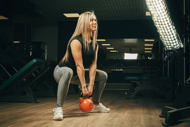Muscular attractive woman in gym lifting dumbbells - Fotoğraf, Görsel