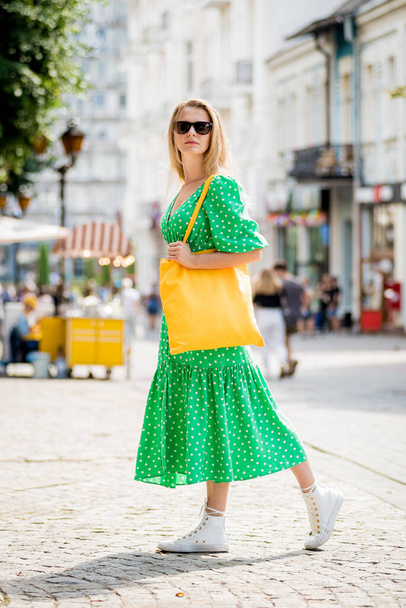 Νεαρή όμορφη γυναίκα με κίτρινο λινό eco bag στο φόντο της πόλης. - Φωτογραφία, εικόνα