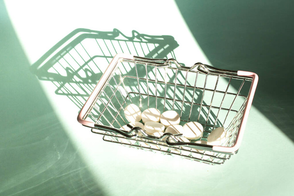 Shopping basket with medicinal pills and tablets on blue background. Pharmacy Shopping Concept. - Photo, Image