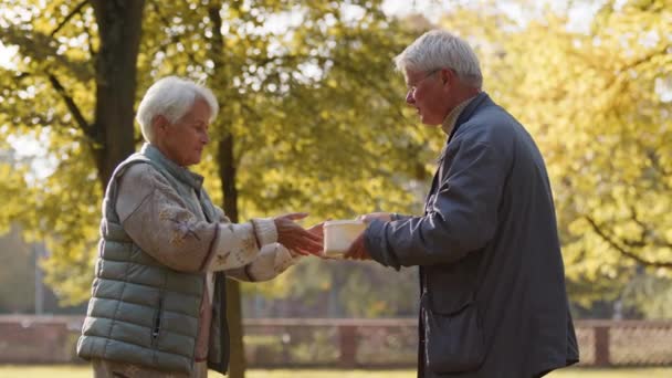 Liefdadigheid en sociale zekerheid. Vrijwilliger man geeft een warme maaltijd aan een oudere vrouw - Video