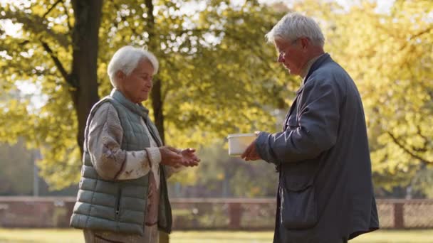 Wohltätigkeit und soziale Fürsorge. Ehrenamtlicher Mann gibt einer älteren Frau eine warme Mahlzeit - Filmmaterial, Video