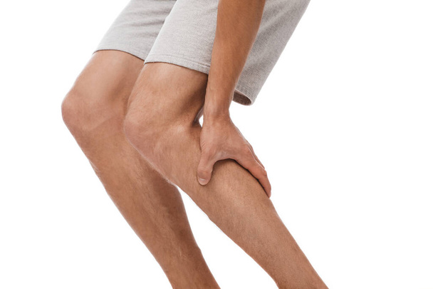 Oříznutý mladý běloch, který trpí bolestí svalů a tiskne ruce k noze - Fotografie, Obrázek