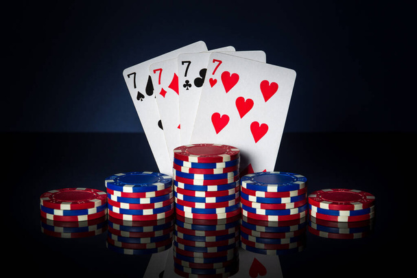 Игра в покер с четырех видов или четырех комбинаций. Чипсы и карты на тёмном столе. Успех и выиграть четыре семерки - Фото, изображение