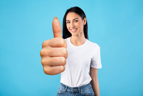 Young brunette woman showing thumb up and smiling - Photo, Image