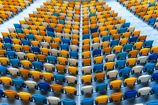 Blurred sitting fans colored plastic chairs at the football stadium background. Closeup of yellow and blue seats on stadium. ArenaLviv Ukraine. - Fotó, kép