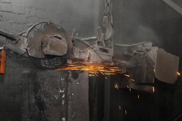 Equipo de molienda pesado suspendido en una cadena con un proceso de gancho y limpia tubos de hormigón armado de hierro fundido en el taller de una planta industrial. - Foto, imagen