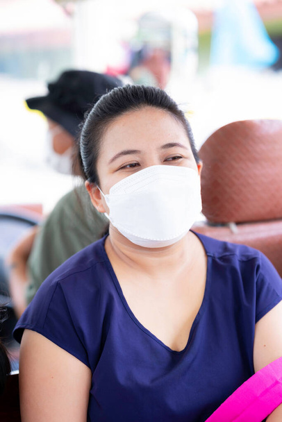 Portrait de femme adulte portant un masque hygiénique blanc en forme de 4D lors d'un voyage à l'extérieur. Nouvelle Normale. Image verticale. Prévenir la pollution par la poussière et le coronavirus (COVID-19). - Photo, image
