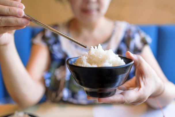 Жінка тримає миску смачно приготованого білого рису
 - Фото, зображення