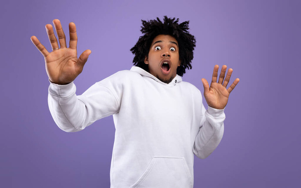 Shocked black teen guy making protection gesture, feeling frightened on violet studio background, panorama - Photo, Image