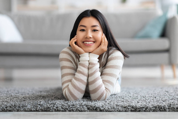 Portrait Of Beautiful Young Asian Female Relaxing On Floor In Living Room - Foto, afbeelding