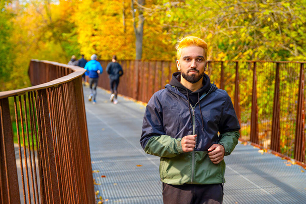 Man with dyed hair in blonde running in the park. - Фото, зображення