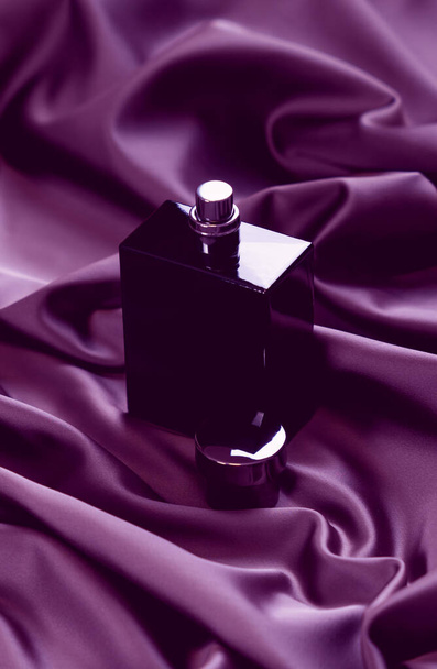 Black perfume bottle on the satin cloth. Toned image. - Zdjęcie, obraz