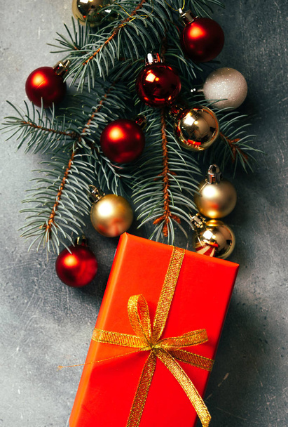 Christmas tree branches, red gift box and Christmas decorations. Top view. Vertical photography. - Фото, изображение