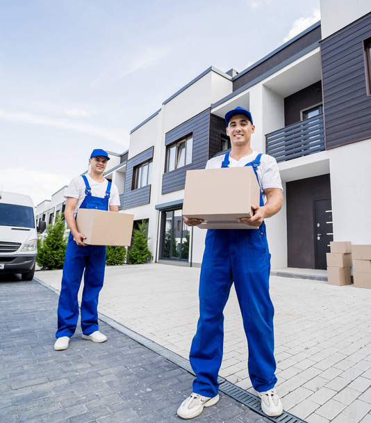 Two removal company workers unloading boxes from minibus into customers home - Zdjęcie, obraz