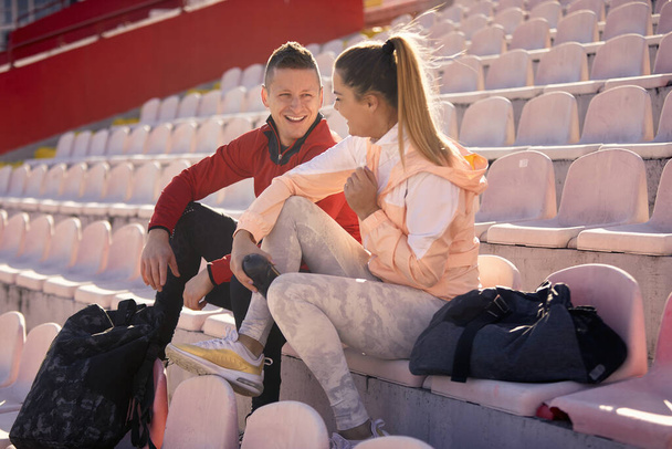 Kaukasische Männer und Frauen reden im Stadion, lächeln, sitzen, schauen einander an - Foto, Bild