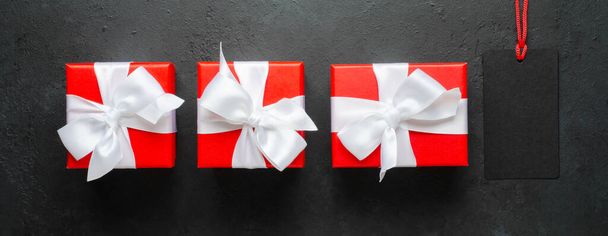 Red gift boxes with white ribbons. Black concrete background. Copy space - Valokuva, kuva