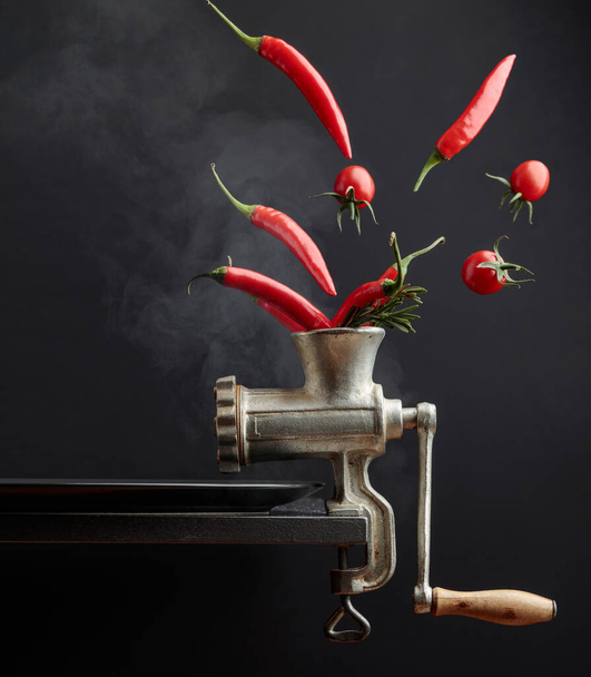 Red hot chili pepper with rosemary, and tomato. The conceptual image on the topic of spicy food. Copy space. - Photo, Image