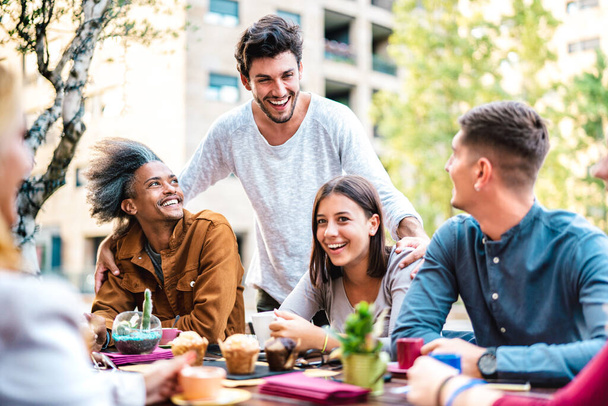 Wielokulturowi przyjaciele pijący cappuccino w kawiarni - Młodzi ludzie bawiący się razem w ogrodzie stołówki na świeżym powietrzu - koncepcja stylu życia ze szczęśliwymi mężczyznami i kobietami w kawiarni na jasnym filtrze - Zdjęcie, obraz