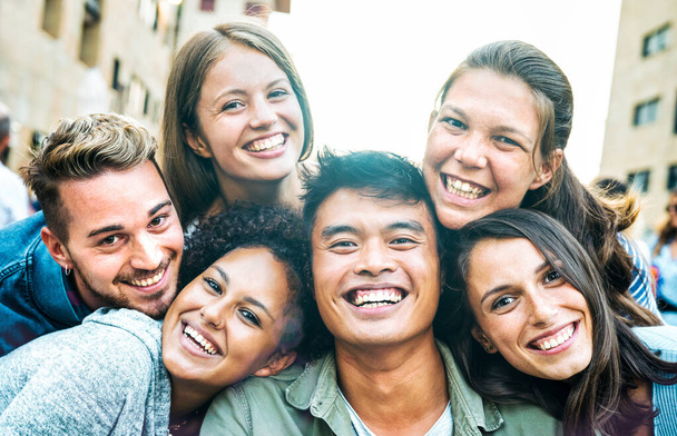 Hombres y mujeres multiculturales tomando selfie fuera con luz de fondo - concepto de estilo de vida milenial feliz en amigos multirraciales jóvenes que se divierten día juntos - Filtro azul brillante con destello de sol - Foto, imagen